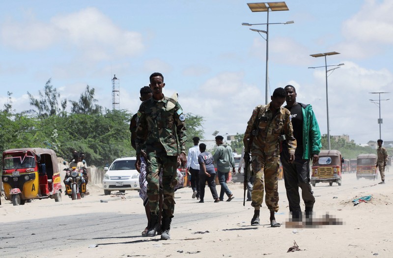 Seorang perwira militer Somalia berjalan melewati sepatu-sepatu yang ditinggalkan di lokasi ledakan yang menargetkan antrean rekrutan muda yang mendaftar di pangkalan militer Damanyo di distrik Hodan, Mogadishu, Somalia, 18 Mei 2025. (REUTERS/Feisal Omar)