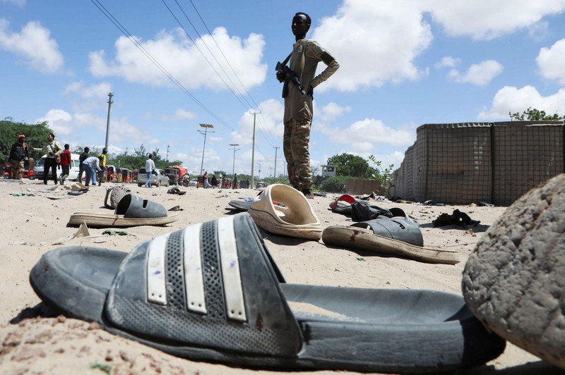 Seorang perwira militer Somalia berjalan melewati sepatu-sepatu yang ditinggalkan di lokasi ledakan yang menargetkan antrean rekrutan muda yang mendaftar di pangkalan militer Damanyo di distrik Hodan, Mogadishu, Somalia, 18 Mei 2025. (REUTERS/Feisal Omar)