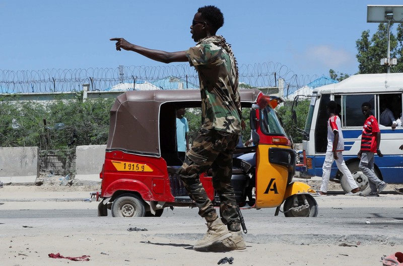 Seorang perwira militer Somalia berjalan melewati sepatu-sepatu yang ditinggalkan di lokasi ledakan yang menargetkan antrean rekrutan muda yang mendaftar di pangkalan militer Damanyo di distrik Hodan, Mogadishu, Somalia, 18 Mei 2025. (REUTERS/Feisal Omar)
