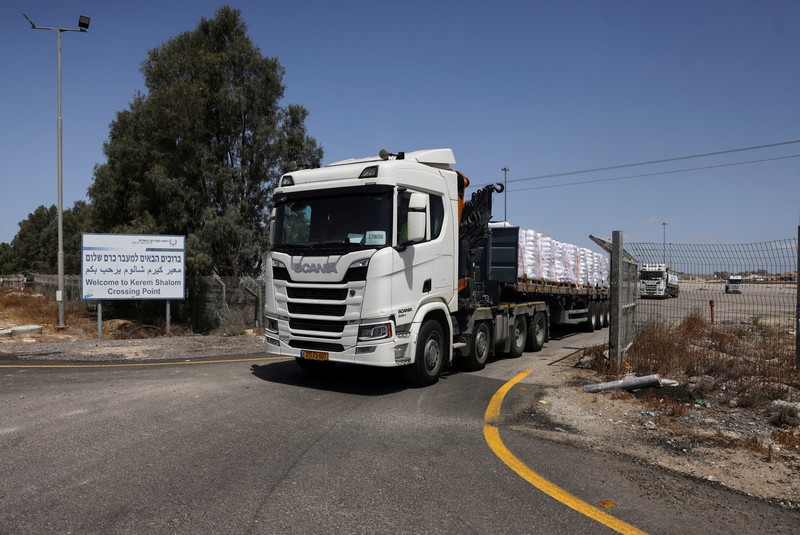 Truk yang membawa bantuan memasuki Gaza, di penyeberangan Kerem Shalom, di sisi penyeberangan Israel, 19 Mei 2025. (REUTERS/Ronen Zvulun)