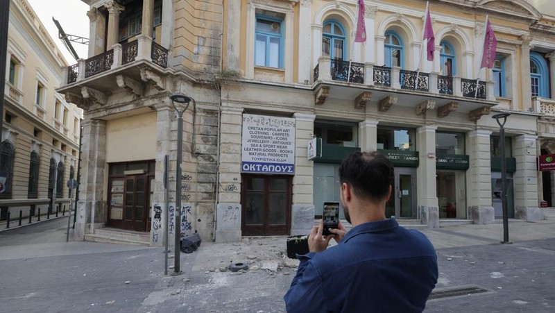 Seorang turis mengambil foto bangunan yang rusak akibat gempa bumi yang melanda Pulau Kreta di Heraklion, Yunani, 22 Mei 2025. (REUTERS/Stefanos Rapanis)