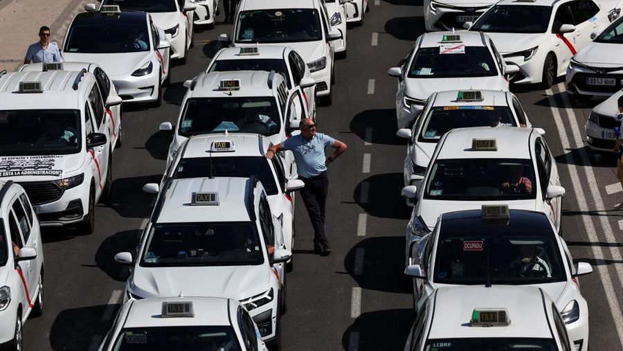 SPAIN-PROTEST/TAXI People cross a street as taxi drivers take part in a protest march against ride-hailing vehicles, in Madrid, Spain, May 28, 2025. REUTERS/Violeta Santos Moura