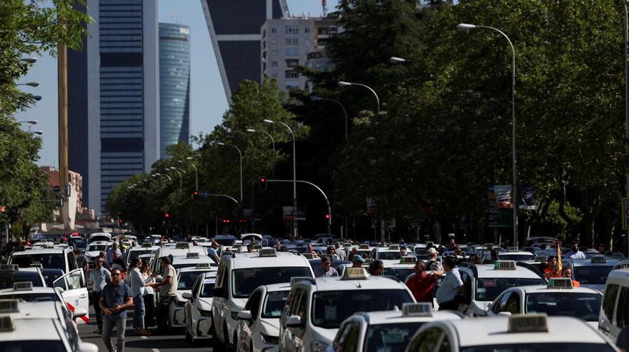 People cross a street as taxi drivers take part in a protest march against ride-hailing vehicles, in Madrid, Spain, May 28, 2025. REUTERS/Violeta Santos Moura