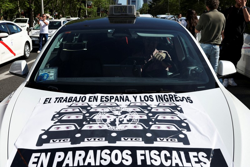 SPAIN-PROTEST/TAXI People cross a street as taxi drivers take part in a protest march against ride-hailing vehicles, in Madrid, Spain, May 28, 2025. REUTERS/Violeta Santos Moura