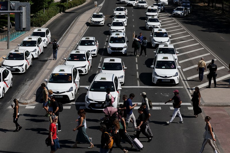 SPAIN-PROTEST/TAXI People cross a street as taxi drivers take part in a protest march against ride-hailing vehicles, in Madrid, Spain, May 28, 2025. REUTERS/Violeta Santos Moura