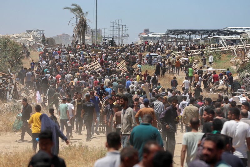 Orang-orang berjalan saat warga Palestina menerima pasokan bantuan dari Yayasan Kemanusiaan Gaza yang didukung AS, dekat wilayah Gaza yang dikenal sebagai koridor Netzarim, 29 Mei 2025. Orang-orang berjalan saat warga Palestina menerima pasokan bantuan dari Yayasan Kemanusiaan Gaza yang didukung AS, dekat wilayah Gaza yang dikenal sebagai koridor Netzarim, 29 Mei 2025. (REUTERS/Ramadan Abed)