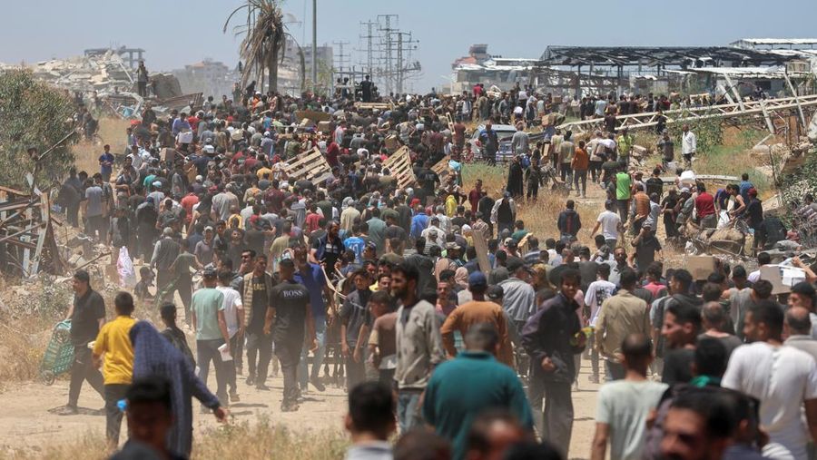 Orang-orang berjalan saat warga Palestina menerima pasokan bantuan dari Yayasan Kemanusiaan Gaza yang didukung AS, dekat wilayah Gaza yang dikenal sebagai koridor Netzarim, 29 Mei 2025. (REUTERS/Ramadan Abed)