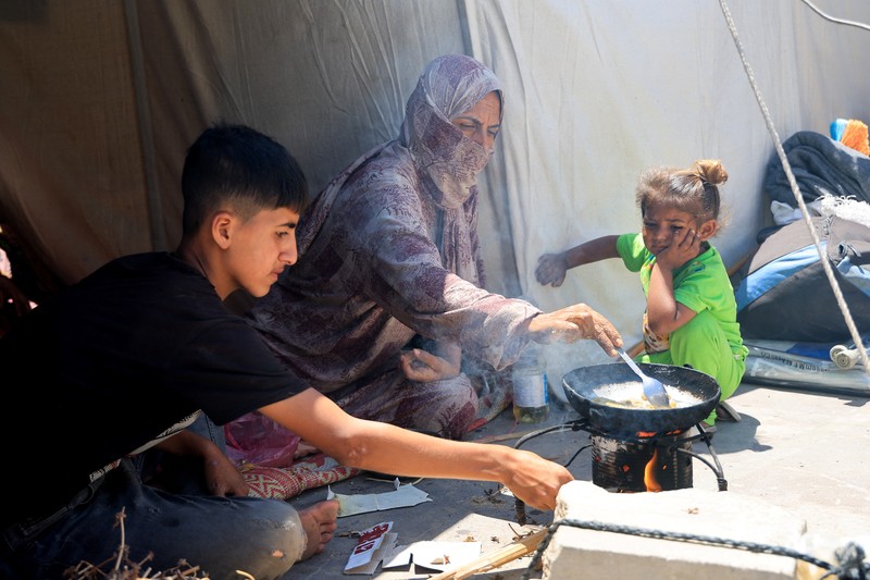 Orang-orang berjalan saat warga Palestina menerima pasokan bantuan dari Yayasan Kemanusiaan Gaza yang didukung AS, dekat wilayah Gaza yang dikenal sebagai koridor Netzarim, 29 Mei 2025. (REUTERS/Ramadan Abed)
