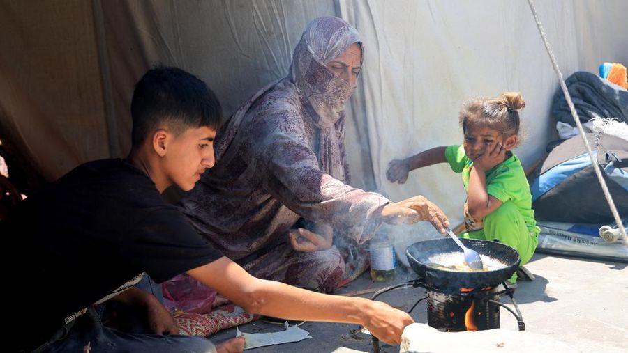 Orang-orang berjalan saat warga Palestina menerima pasokan bantuan dari Yayasan Kemanusiaan Gaza yang didukung AS, dekat wilayah Gaza yang dikenal sebagai koridor Netzarim, 29 Mei 2025. (REUTERS/Ramadan Abed)