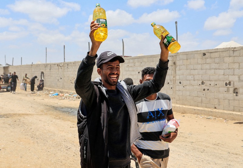 Orang-orang berjalan saat warga Palestina menerima pasokan bantuan dari Yayasan Kemanusiaan Gaza yang didukung AS, dekat wilayah Gaza yang dikenal sebagai koridor Netzarim, 29 Mei 2025. (REUTERS/Ramadan Abed)