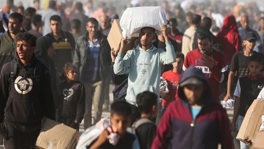 Orang-orang berjalan saat warga Palestina menerima pasokan bantuan dari Yayasan Kemanusiaan Gaza yang didukung AS, dekat wilayah Gaza yang dikenal sebagai koridor Netzarim, 29 Mei 2025. (REUTERS/Ramadan Abed)