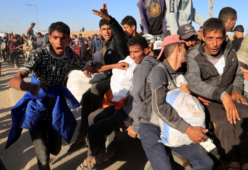 Orang-orang berjalan saat warga Palestina menerima pasokan bantuan dari Yayasan Kemanusiaan Gaza yang didukung AS, dekat wilayah Gaza yang dikenal sebagai koridor Netzarim, 29 Mei 2025. (REUTERS/Ramadan Abed)