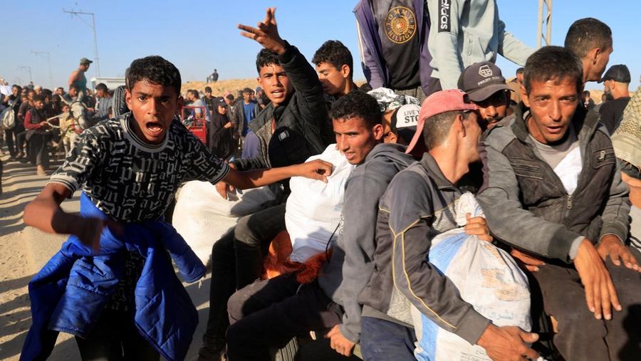 Orang-orang berjalan saat warga Palestina menerima pasokan bantuan dari Yayasan Kemanusiaan Gaza yang didukung AS, dekat wilayah Gaza yang dikenal sebagai koridor Netzarim, 29 Mei 2025. (REUTERS/Ramadan Abed)