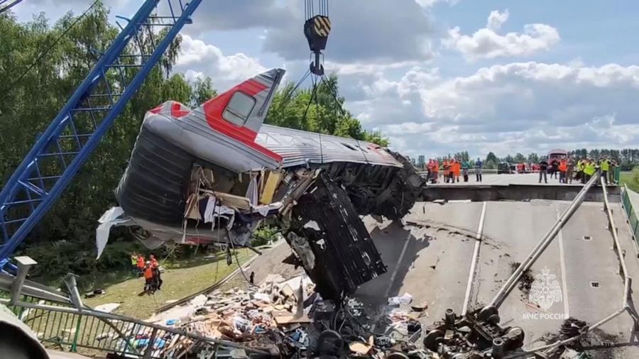 Petugas layanan darurat berada pada lokasi gerbong kereta yang rusak setelah jembatan jalan runtuh ke rel kereta api di wilayah Bryansk, Rusia, Minggu (1/6/2025). (Russian Emergencies Ministry/Handout via REUTERS)