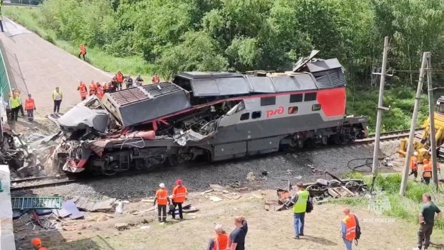 Petugas layanan darurat berada pada lokasi gerbong kereta yang rusak setelah jembatan jalan runtuh ke rel kereta api di wilayah Bryansk, Rusia, Minggu (1/6/2025). (Russian Emergencies Ministry/Handout via REUTERS)