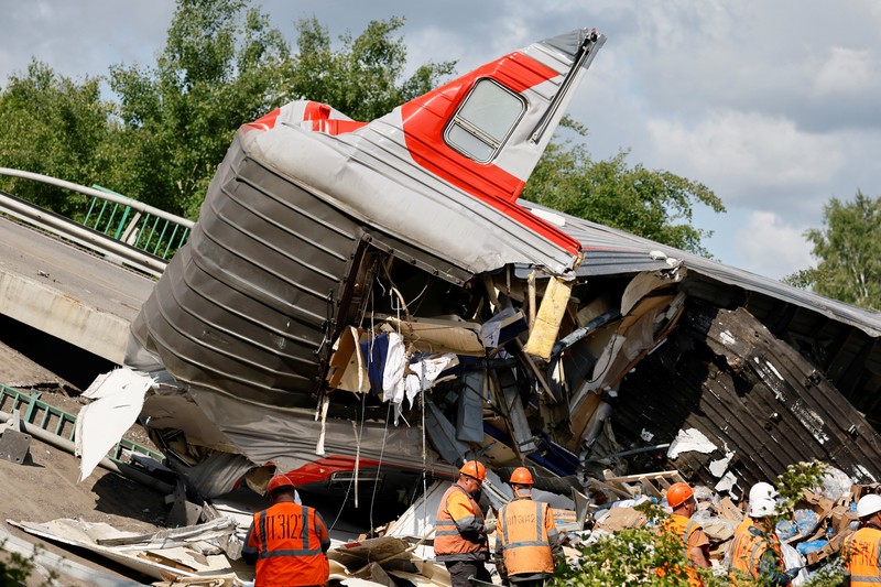 Petugas layanan darurat berada pada lokasi gerbong kereta yang rusak setelah jembatan jalan runtuh ke rel kereta api di wilayah Bryansk, Rusia, Minggu (1/6/2025). (Russian Emergencies Ministry/Handout via REUTERS)