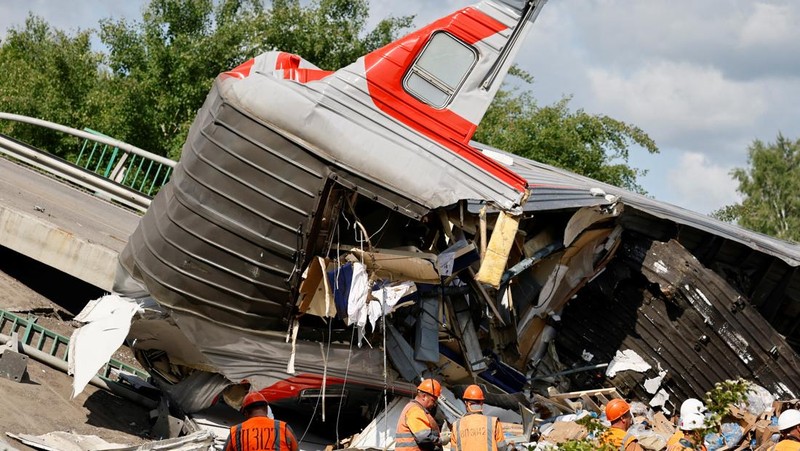 Petugas layanan darurat berada pada lokasi gerbong kereta yang rusak setelah jembatan jalan runtuh ke rel kereta api di wilayah Bryansk, Rusia, Minggu (1/6/2025). (Russian Emergencies Ministry/Handout via REUTERS)