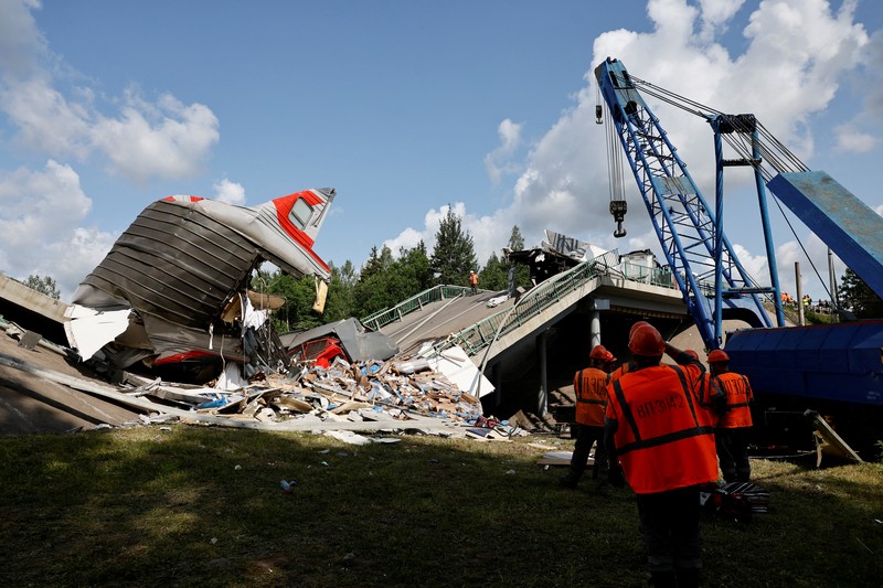Petugas layanan darurat berada pada lokasi gerbong kereta yang rusak setelah jembatan jalan runtuh ke rel kereta api di wilayah Bryansk, Rusia, Minggu (1/6/2025). (Russian Emergencies Ministry/Handout via REUTERS)