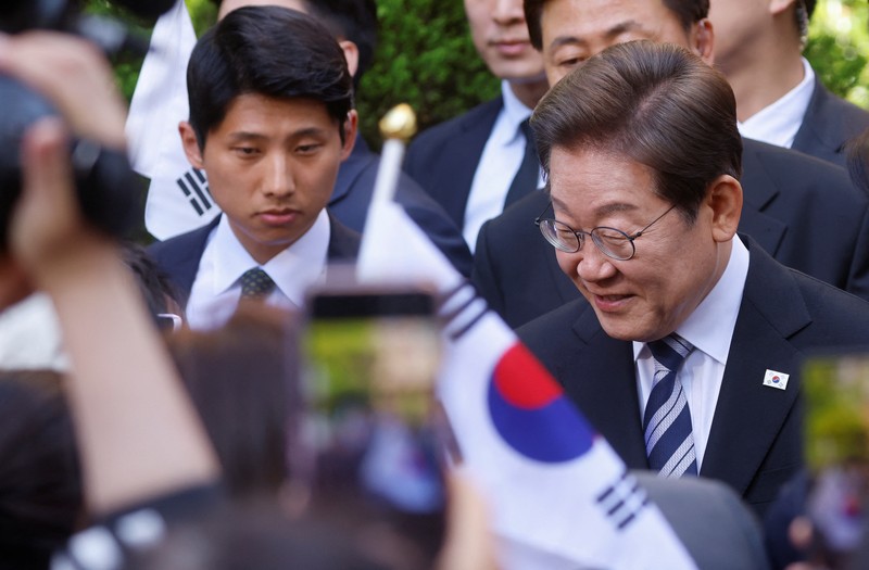 Lee Jae-myung, kandidat presiden dari Partai Demokrat Korea Selatan, dan istrinya Kim Hye-kyung memberi isyarat, di depan Majelis Nasional di Seoul, Korea Selatan, 4 Juni 2025. (REUTERS/Kim Hong-Ji)