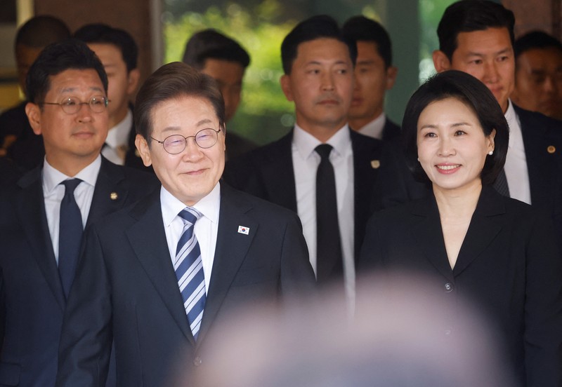 Lee Jae-myung, kandidat presiden dari Partai Demokrat Korea Selatan, dan istrinya Kim Hye-kyung memberi isyarat, di depan Majelis Nasional di Seoul, Korea Selatan, 4 Juni 2025. (REUTERS/Kim Hong-Ji)