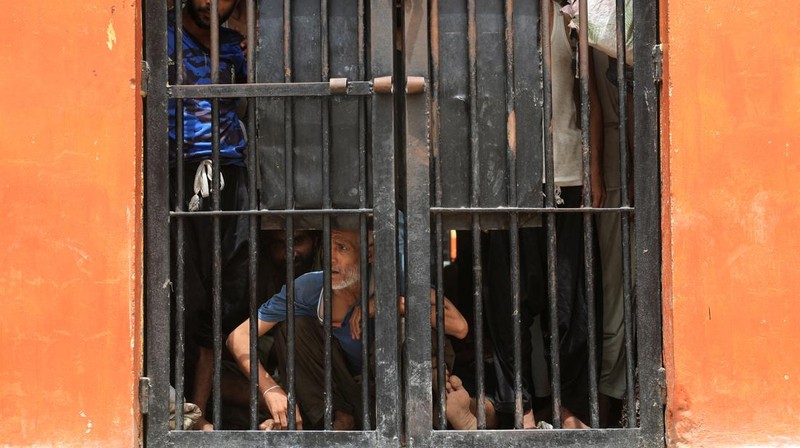 Seorang petugas polisi dengan tongkat bereaksi saat membubarkan anggota keluarga tahanan, setelah puluhan tahanan melarikan diri dari Penjara Malir, di pinggiran Karachi, Pakistan, 3 Juni 2025. (REUTERS/Akhtar Soomro)