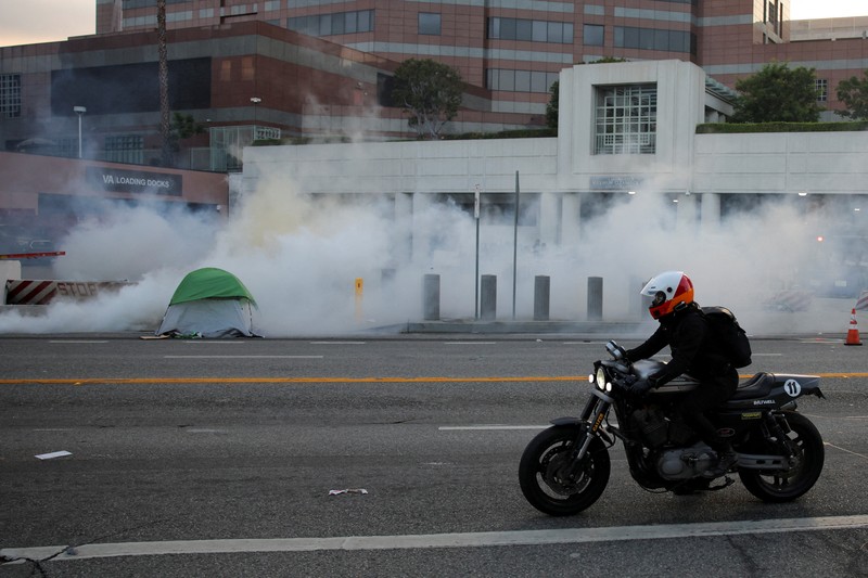 A Mexican flag waves as a car burns in flames following multiple detentions by Immigration and Customs Enforcement (ICE), in the Los Angeles County city of Paramount, California, U.S., June 7, 2025.   REUTERS/Daniel Cole