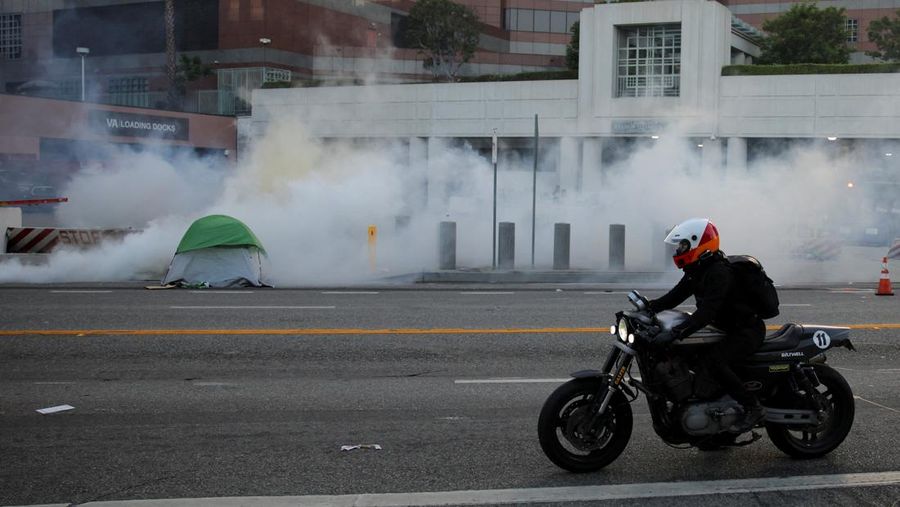 A Mexican flag waves as a car burns in flames following multiple detentions by Immigration and Customs Enforcement (ICE), in the Los Angeles County city of Paramount, California, U.S., June 7, 2025.   REUTERS/Daniel Cole