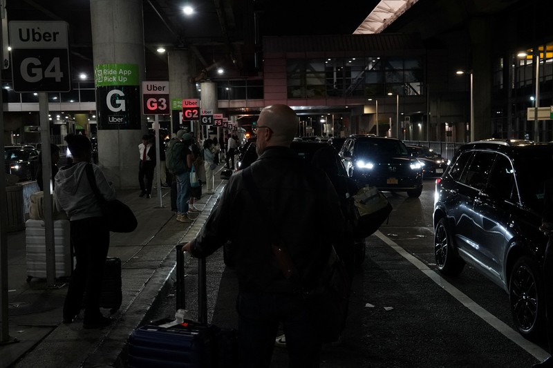 A traveler waits for his vehicle at an Uber passenger pick-up area at Terminal 8 at John F. Kennedy International Airport, ahead of U.S. President Donald Trump?s reinstatement of a new travel ban barring citizens of 12 countries from entering the U.S., in New York, U.S., June 8, 2025. REUTERS/Bing Guan