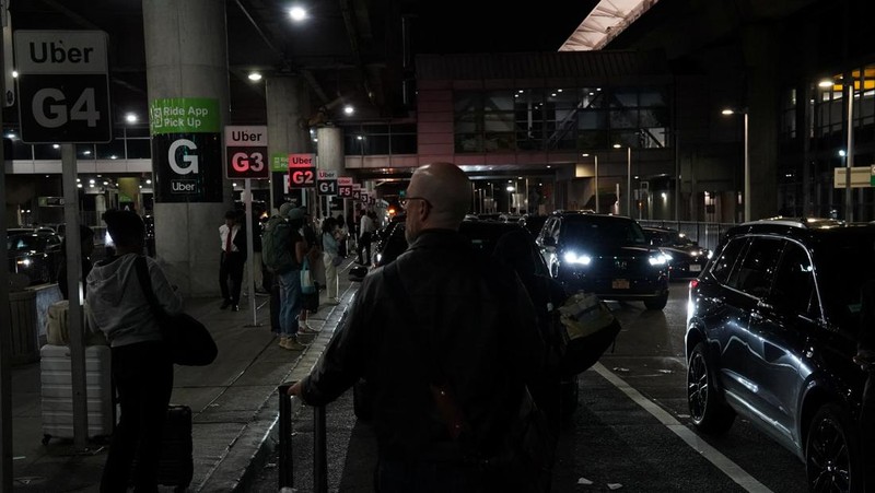 A traveler waits for his vehicle at an Uber passenger pick-up area at Terminal 8 at John F. Kennedy International Airport, ahead of U.S. President Donald Trump?s reinstatement of a new travel ban barring citizens of 12 countries from entering the U.S., in New York, U.S., June 8, 2025. REUTERS/Bing Guan