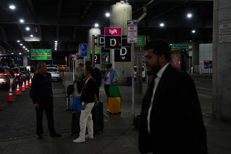 USA-TRAVEL/ A traveler waits for his vehicle at an Uber passenger pick-up area at Terminal 8 at John F. Kennedy International Airport, ahead of U.S. President Donald Trump?s reinstatement of a new travel ban barring citizens of 12 countries from entering the U.S., in New York, U.S., June 8, 2025. REUTERS/Bing Guan