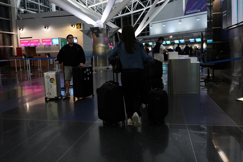 A traveler waits for his vehicle at an Uber passenger pick-up area at Terminal 8 at John F. Kennedy International Airport, ahead of U.S. President Donald Trump?s reinstatement of a new travel ban barring citizens of 12 countries from entering the U.S., in New York, U.S., June 8, 2025. REUTERS/Bing Guan