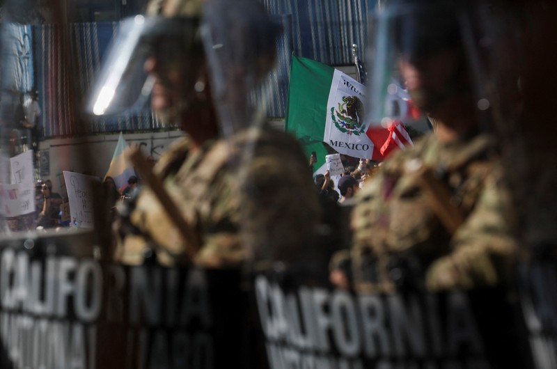 Para demonstran berkumpul di depan pasukan Garda Nasional California dan petugas penegak hukum, saat protes terhadap pemeriksaan imigrasi berlanjut, di Los Angeles, California, AS, 9 Juni 2025. Para demonstran berkumpul di depan pasukan Garda Nasional California dan petugas penegak hukum, saat protes terhadap pemeriksaan imigrasi berlanjut, di Los Angeles, California, AS, 9 Juni 2025. (REUTERS/Daniel Cole)