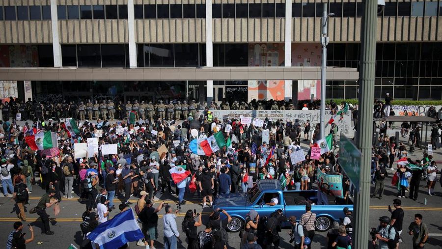 Para demonstran berkumpul di depan pasukan Garda Nasional California dan petugas penegak hukum, saat protes terhadap pemeriksaan imigrasi berlanjut, di Los Angeles, California, AS, 9 Juni 2025. Para demonstran berkumpul di depan pasukan Garda Nasional California dan petugas penegak hukum, saat protes terhadap pemeriksaan imigrasi berlanjut, di Los Angeles, California, AS, 9 Juni 2025. (REUTERS/Daniel Cole)