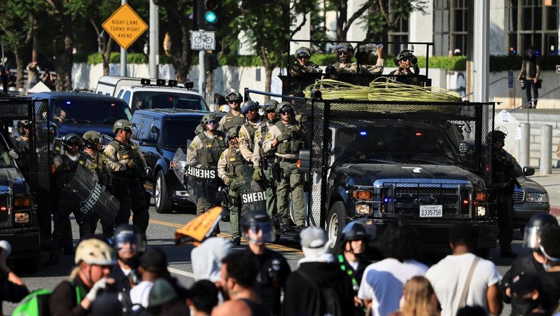 Para demonstran berkumpul di depan pasukan Garda Nasional California dan petugas penegak hukum, saat protes terhadap pemeriksaan imigrasi berlanjut, di Los Angeles, California, AS, 9 Juni 2025. (REUTERS/Daniel Cole)