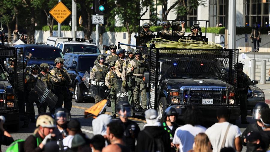 Para demonstran berkumpul di depan pasukan Garda Nasional California dan petugas penegak hukum, saat protes terhadap pemeriksaan imigrasi berlanjut, di Los Angeles, California, AS, 9 Juni 2025. Para demonstran berkumpul di depan pasukan Garda Nasional California dan petugas penegak hukum, saat protes terhadap pemeriksaan imigrasi berlanjut, di Los Angeles, California, AS, 9 Juni 2025. (REUTERS/Daniel Cole)