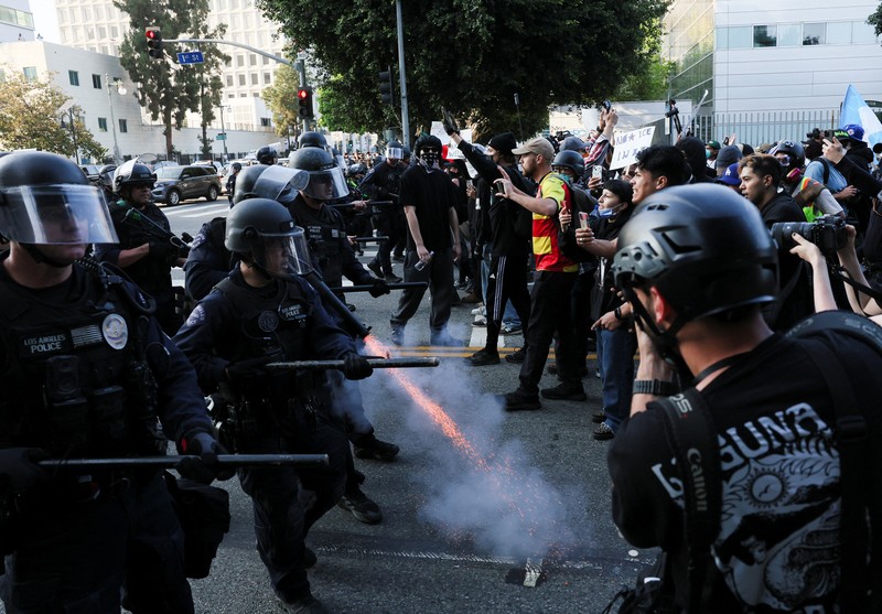 Para demonstran berkumpul di depan pasukan Garda Nasional California dan petugas penegak hukum, saat protes terhadap pemeriksaan imigrasi berlanjut, di Los Angeles, California, AS, 9 Juni 2025. Para demonstran berkumpul di depan pasukan Garda Nasional California dan petugas penegak hukum, saat protes terhadap pemeriksaan imigrasi berlanjut, di Los Angeles, California, AS, 9 Juni 2025. (REUTERS/Daniel Cole)