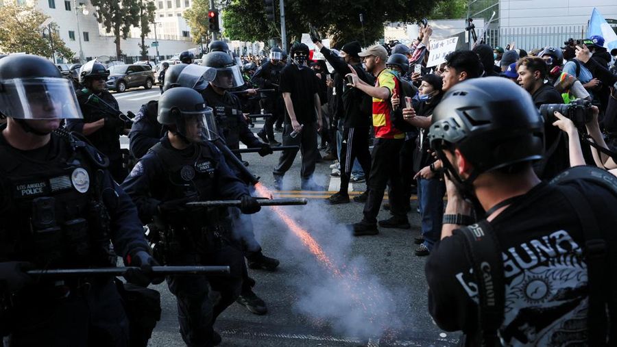 Para demonstran berkumpul di depan pasukan Garda Nasional California dan petugas penegak hukum, saat protes terhadap pemeriksaan imigrasi berlanjut, di Los Angeles, California, AS, 9 Juni 2025. Para demonstran berkumpul di depan pasukan Garda Nasional California dan petugas penegak hukum, saat protes terhadap pemeriksaan imigrasi berlanjut, di Los Angeles, California, AS, 9 Juni 2025. (REUTERS/Daniel Cole)