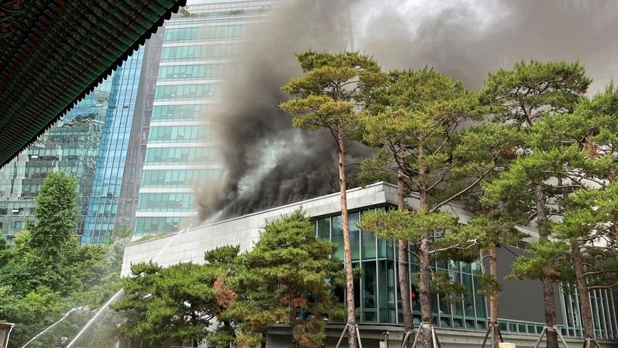 Orang-orang berjalan melewati mobil pemadam kebakaran saat kebakaran terjadi di gedung Museum Buddha Pusat di sebelah Kuil Jogye di Seoul, Korea Selatan, 10 Juni 2025. (REUTERS/Josh Smith)