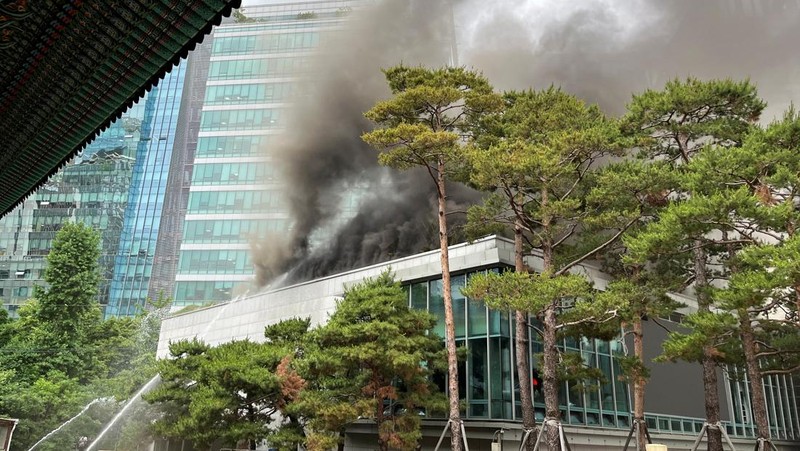 Orang-orang berjalan melewati mobil pemadam kebakaran saat kebakaran terjadi di gedung Museum Buddha Pusat di sebelah Kuil Jogye di Seoul, Korea Selatan, 10 Juni 2025. (REUTERS/Josh Smith)