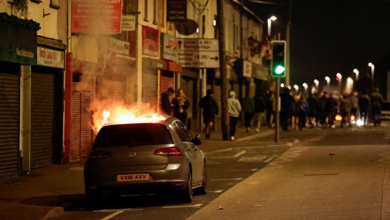 Seorang petugas polisi berjaga selama malam kedua kerusuhan, di Ballymena, Irlandia Utara, 10 Juni 2025. (REUTERS/Clodagh Kilcoyne)