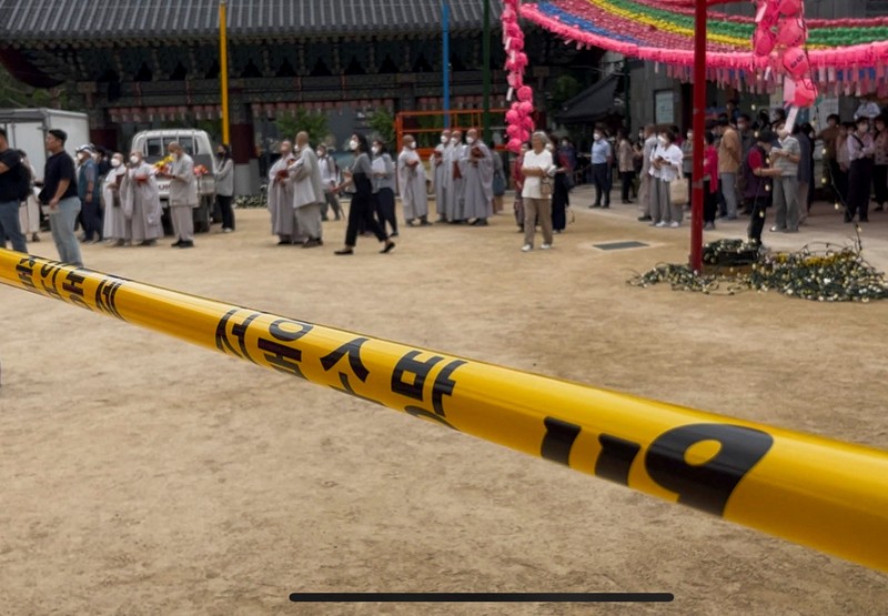 Orang-orang berjalan melewati mobil pemadam kebakaran saat kebakaran terjadi di gedung Museum Buddha Pusat di sebelah Kuil Jogye di Seoul, Korea Selatan, 10 Juni 2025. (REUTERS/Josh Smith)