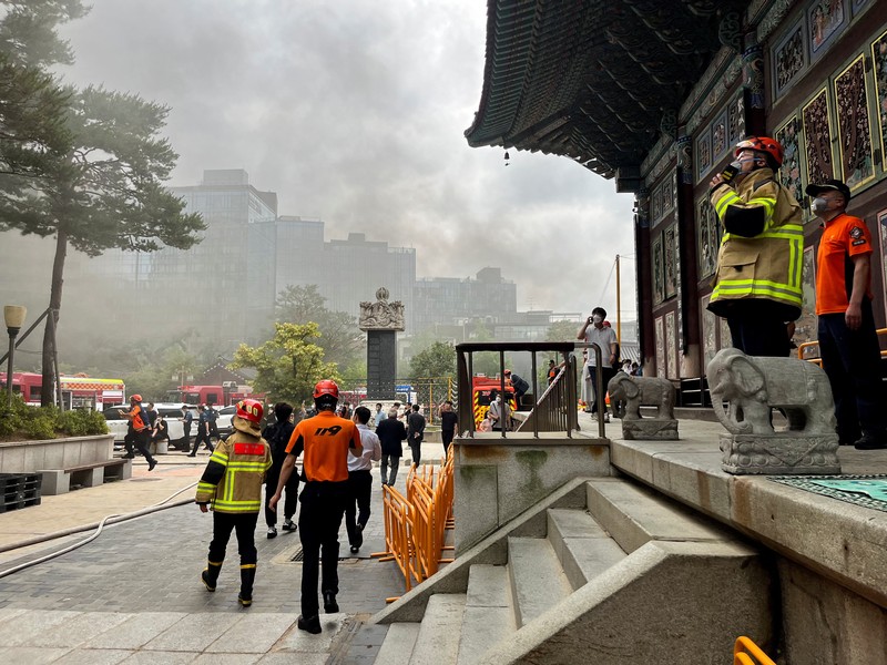 Orang-orang berjalan melewati mobil pemadam kebakaran saat kebakaran terjadi di gedung Museum Buddha Pusat di sebelah Kuil Jogye di Seoul, Korea Selatan, 10 Juni 2025. (REUTERS/Josh Smith)