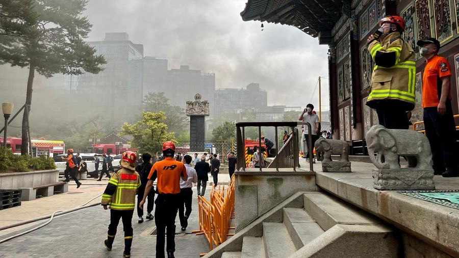 Orang-orang berjalan melewati mobil pemadam kebakaran saat kebakaran terjadi di gedung Museum Buddha Pusat di sebelah Kuil Jogye di Seoul, Korea Selatan, 10 Juni 2025. (REUTERS/Josh Smith)