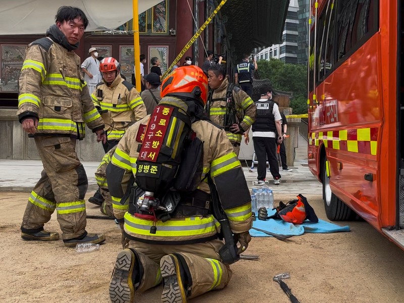 Orang-orang berjalan melewati mobil pemadam kebakaran saat kebakaran terjadi di gedung Museum Buddha Pusat di sebelah Kuil Jogye di Seoul, Korea Selatan, 10 Juni 2025. (REUTERS/Josh Smith)