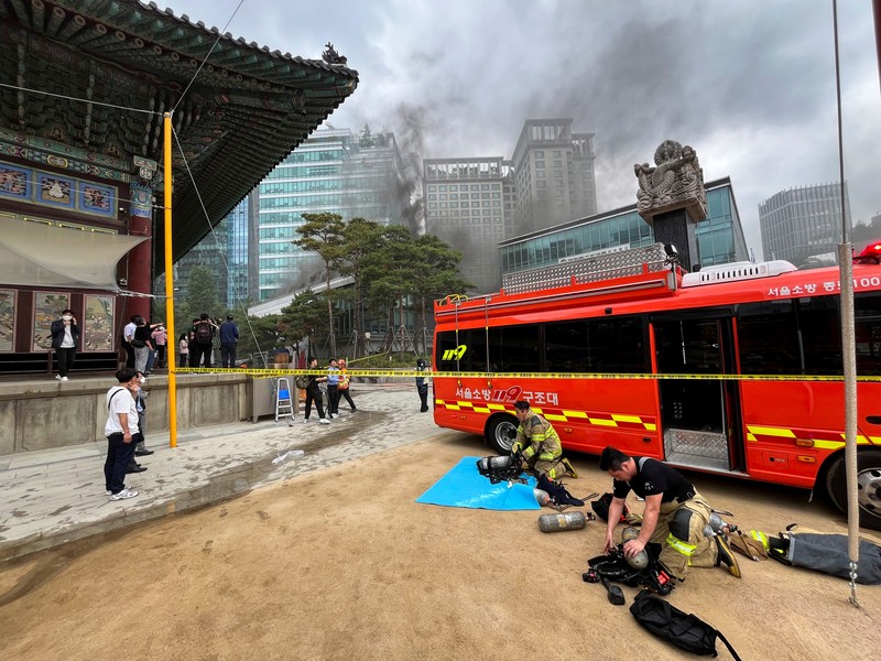 Orang-orang berjalan melewati mobil pemadam kebakaran saat kebakaran terjadi di gedung Museum Buddha Pusat di sebelah Kuil Jogye di Seoul, Korea Selatan, 10 Juni 2025. (REUTERS/Josh Smith)