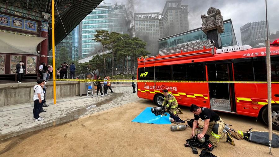 Orang-orang berjalan melewati mobil pemadam kebakaran saat kebakaran terjadi di gedung Museum Buddha Pusat di sebelah Kuil Jogye di Seoul, Korea Selatan, 10 Juni 2025. (REUTERS/Josh Smith)