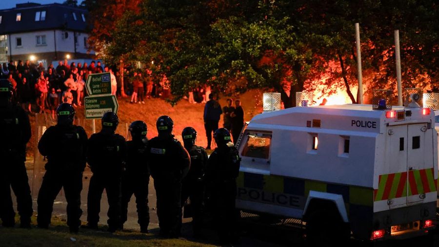 Seorang petugas polisi berjaga selama malam kedua kerusuhan, di Ballymena, Irlandia Utara, 10 Juni 2025. (REUTERS/Clodagh Kilcoyne)