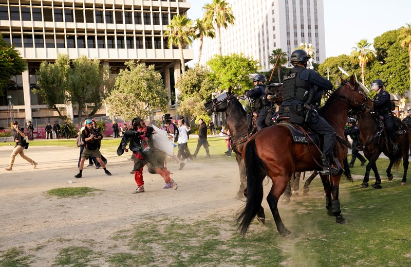 USA-MIGRATION/PROTEST-LOS ANGELES Police officers ride horses as they attempt to disperse protesters demonstrating against federal immigration sweeps, in downtown Los Angeles, California, U.S. June 11, 2025. REUTERS/David Ryder