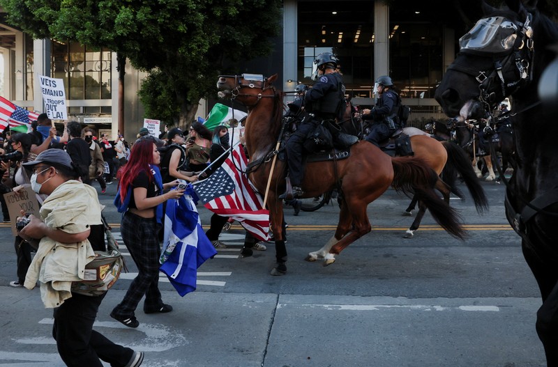 USA-MIGRATION/PROTEST-LOS ANGELES Police officers ride horses as they attempt to disperse protesters demonstrating against federal immigration sweeps, in downtown Los Angeles, California, U.S. June 11, 2025. REUTERS/David Ryder