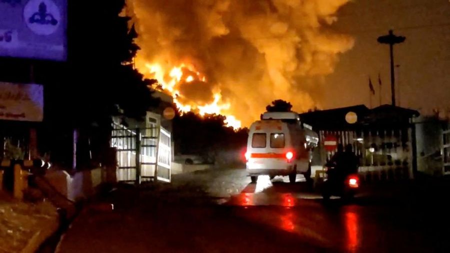 Orang-orang menyaksikan dari jembatan saat api dari serangan Israel membubung dari depot minyak Sharan, menyusul serangan Israel terhadap Iran, di Teheran, Iran, 15 Juni 2025. (Majid Asgaripour/WANA (West Asia News Agency) via REUTERS)